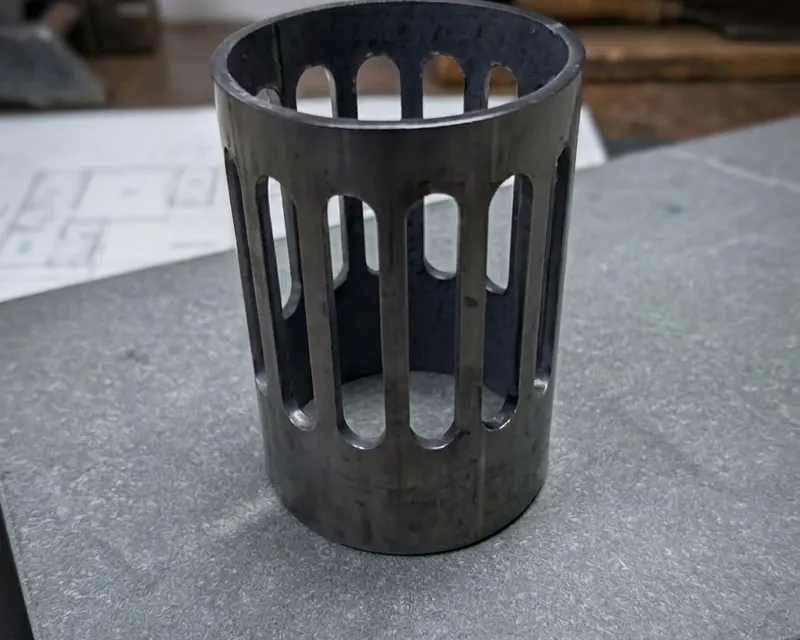 Mild steel cylindrical basket with precision-cut vertical slot pattern